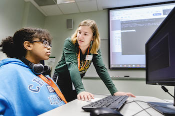 A mentor advises a student in front of a computer